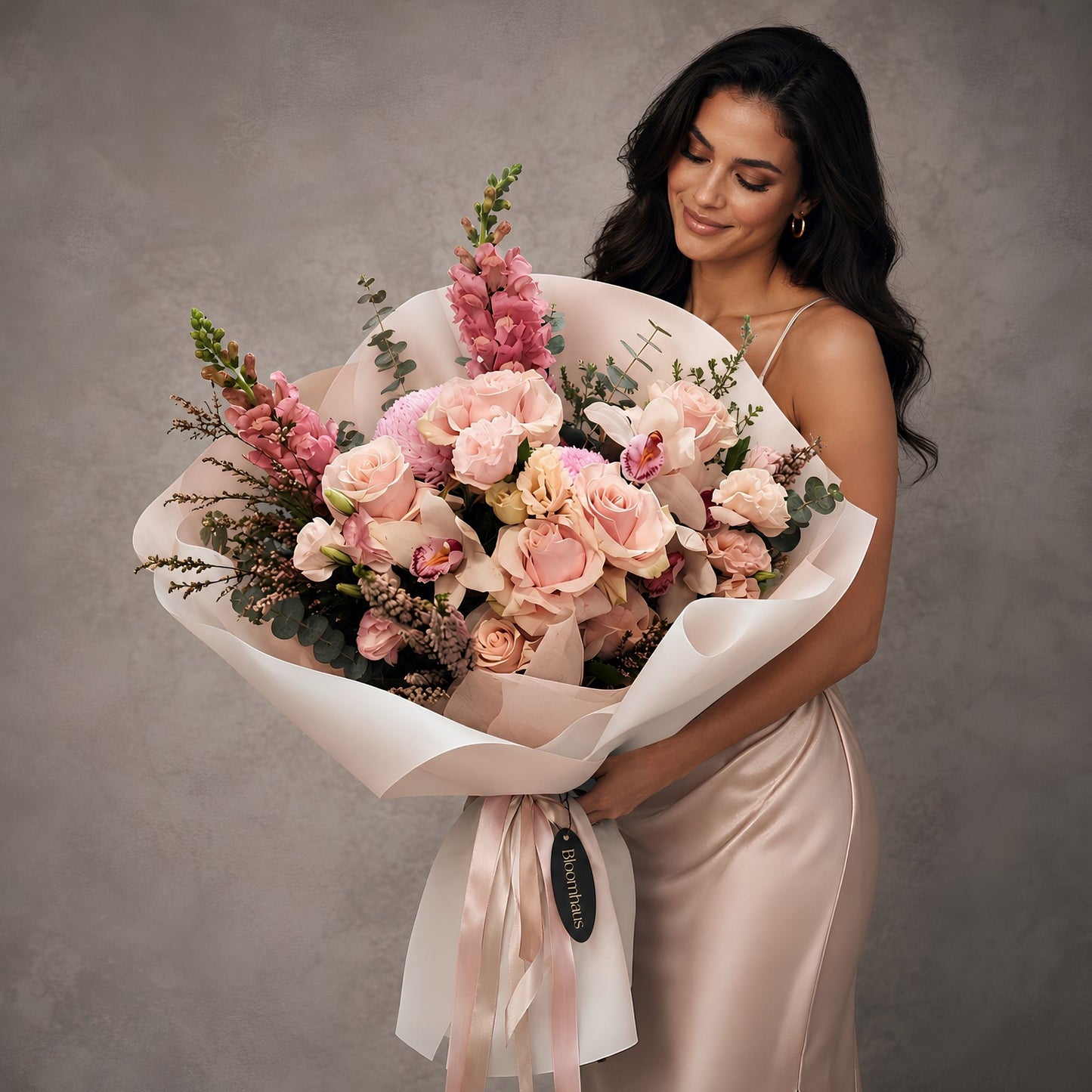 FLORAL PINK BOUQUET WITH GLAMOUROUS WOMAN HOLDING AGAINST A GREY WALL