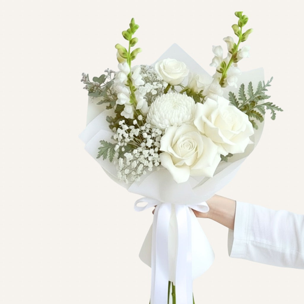 Bouquet of white flowers with greenery held by a person against a light background Bloomhaus Melbourne flower delivery
