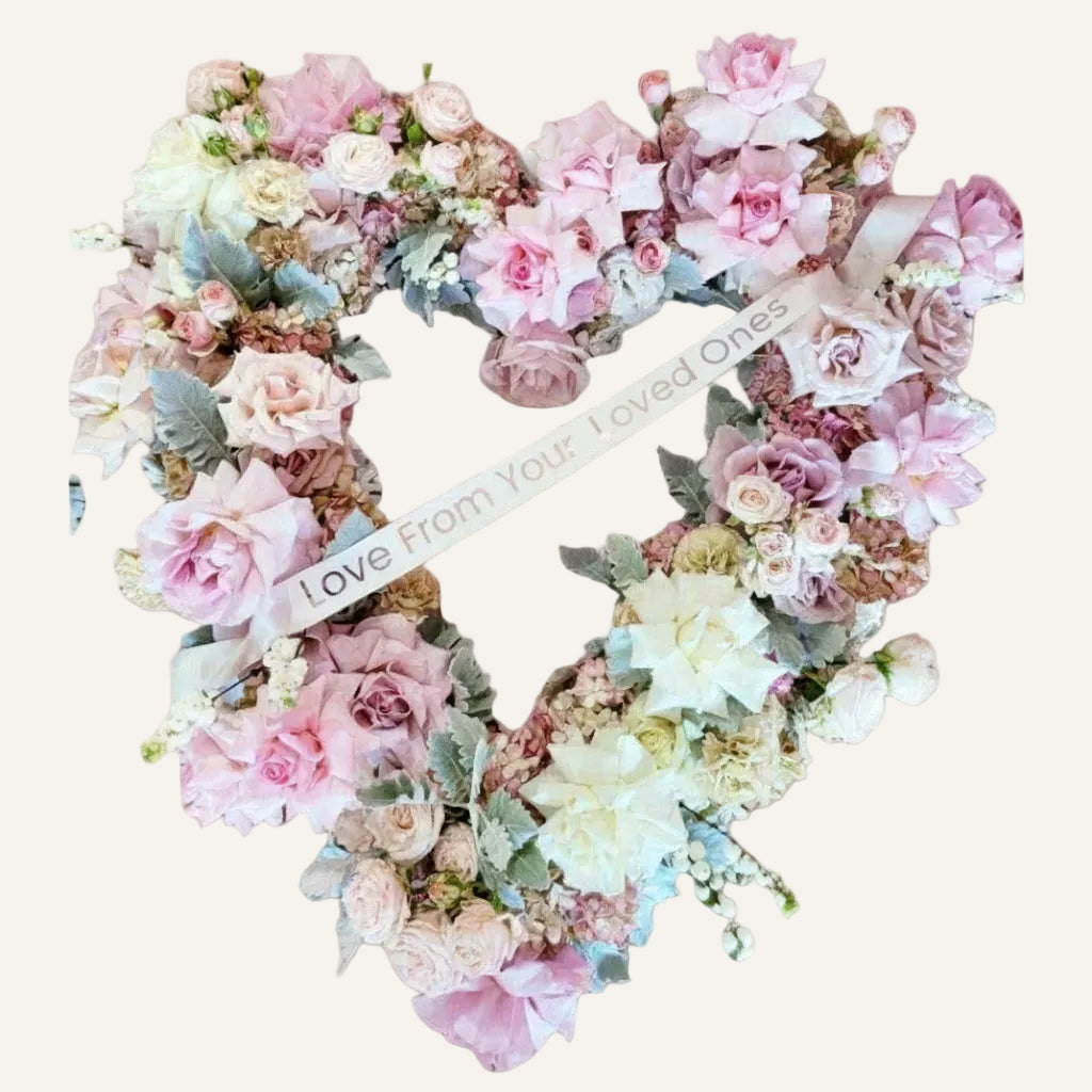 Heart shaped Sympathy Wreath pastel coloured pink roses and white roses with seasonal flowers an ribbon with message