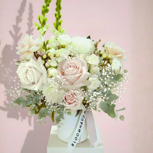 Floral arrangement with white and pink roses in a white vase on a pink background