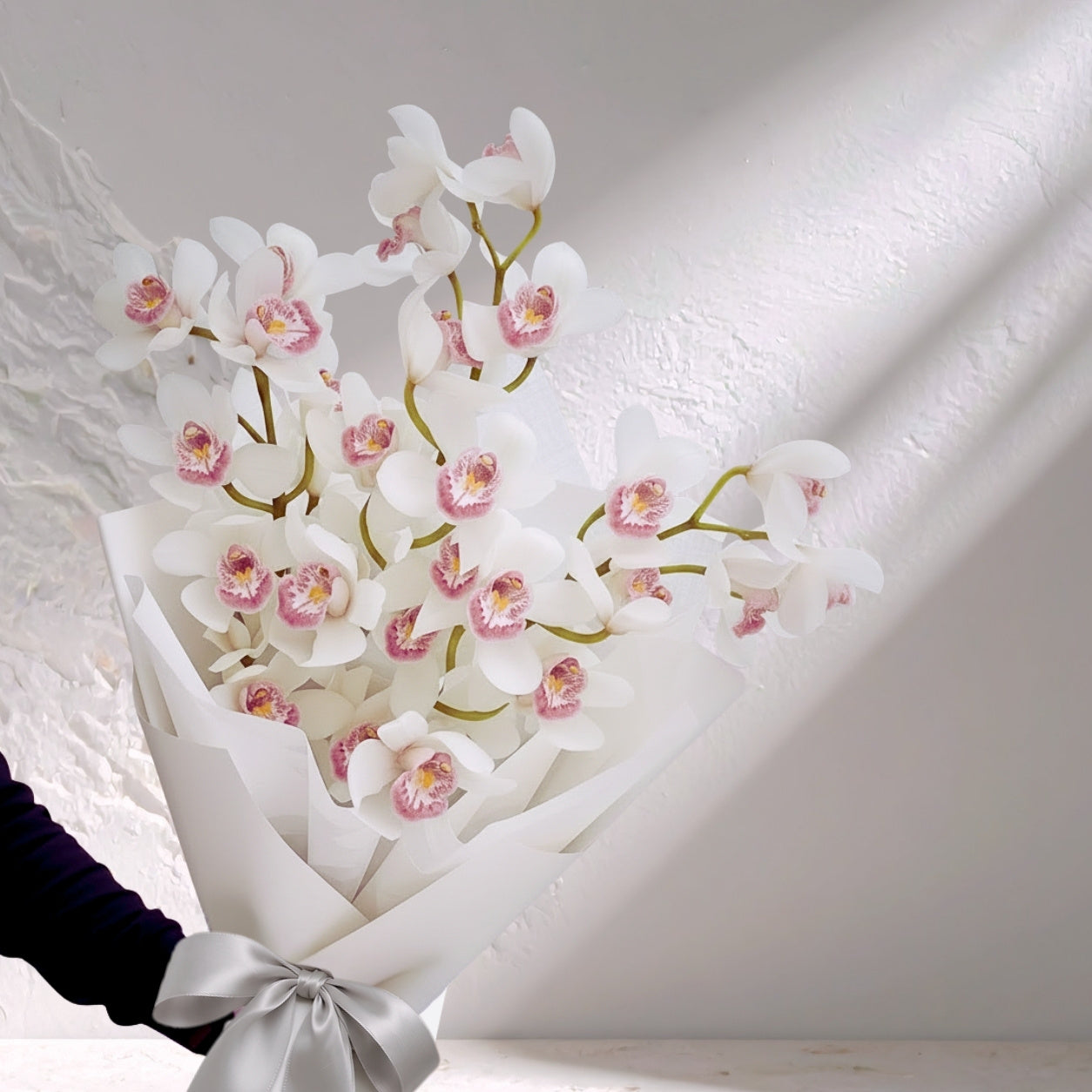 Pink Cymbidium orchid flowers in a lush bloom display by BLOOMHAUS MELBOURNE, showcasing vibrant, elegant orchid blossoms.
