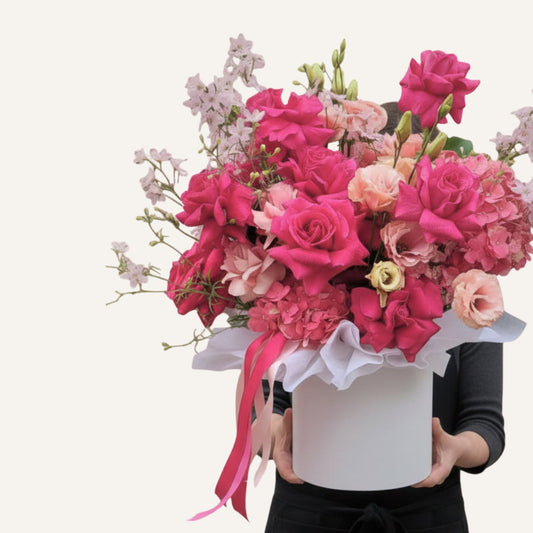Hatbox  of pink and white flowers in a box held by a person on a white background Bloomhaus Melbourne Hampton 