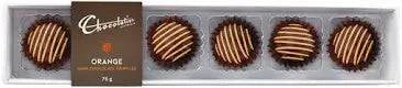 A sleek, rectangular box containing five Chocolatier Dark Chocolate Orange Truffles, each nestled in a black paper cup. The truffles are round, coated in smooth dark chocolate, and elegantly decorated with white chocolate orange stripes. A brown label on the box displays the Chocolatier logo, the word 'Orange,' and the weight of 75g. The packaging has a luxurious and sophisticated design, making it an ideal gift or treat."