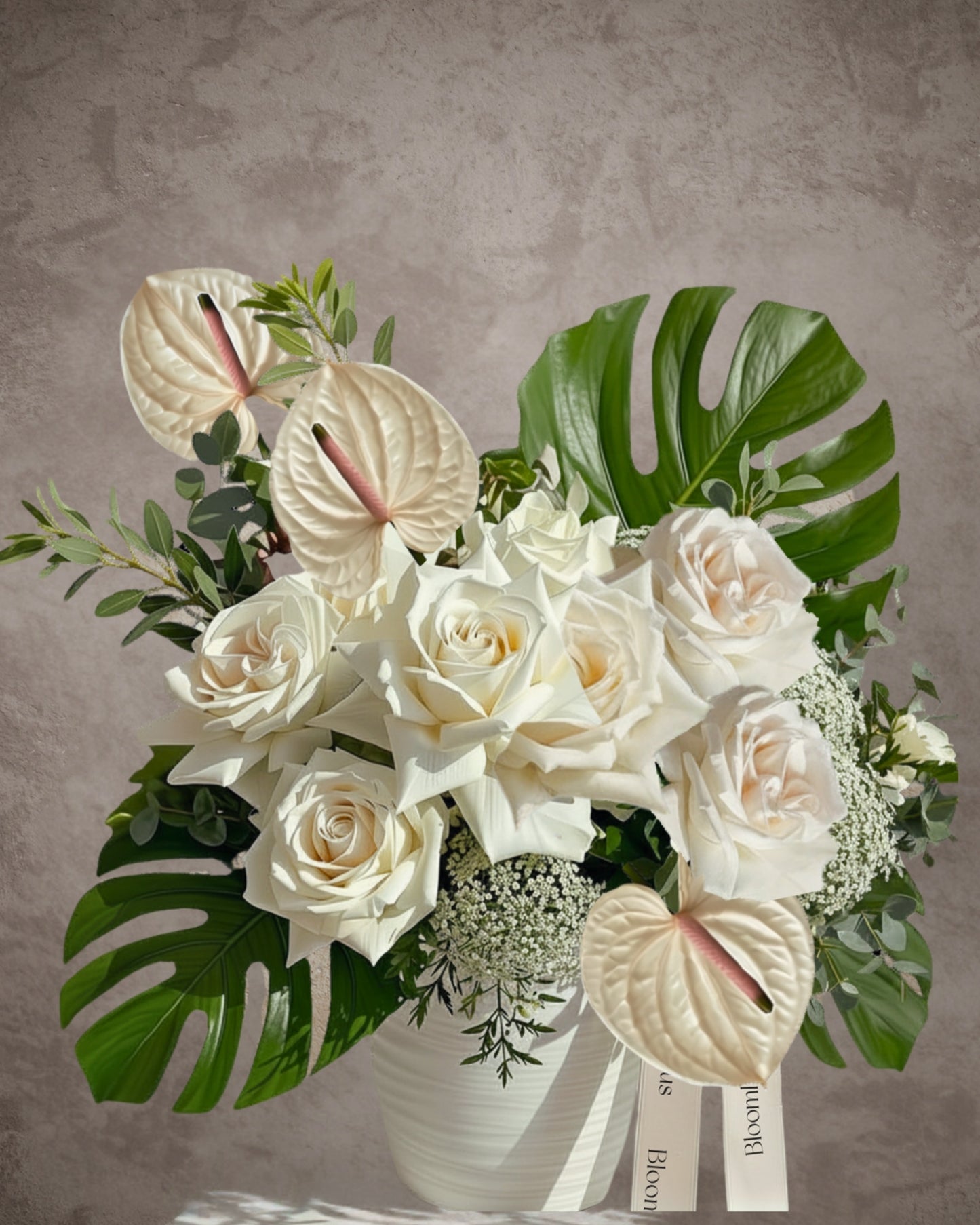 Elegant flower arrangement with white roses, anthuriums, and seasonal flowers in a ceramic pot by BLOOMHAUS MELBOURNE