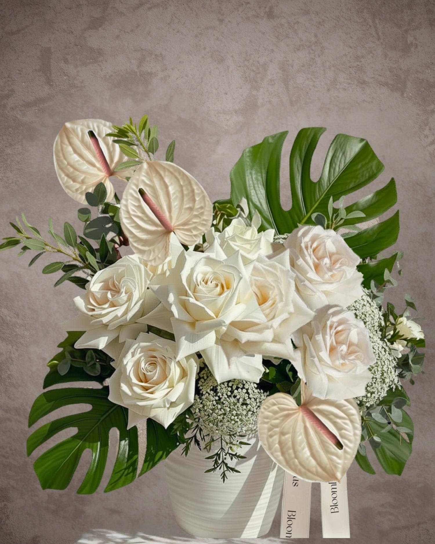 Elegant flower arrangement with white roses, anthuriums, and seasonal flowers in a ceramic pot by BLOOMHAUS MELBOURNE