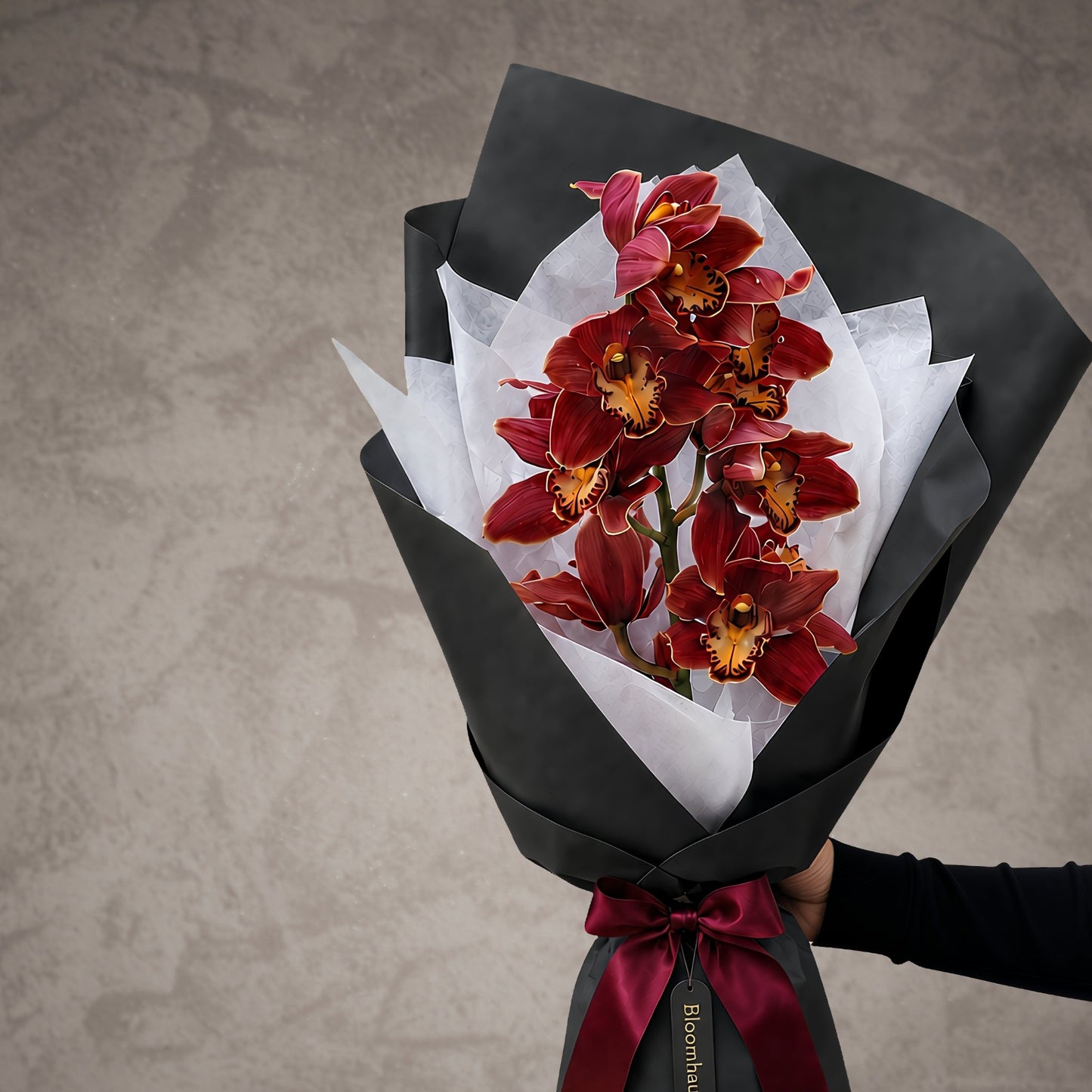 Luxury red cymbidium orchid bouquet in sculptural white wrapping with silver ribbon by Bloomhaus Melbourne.