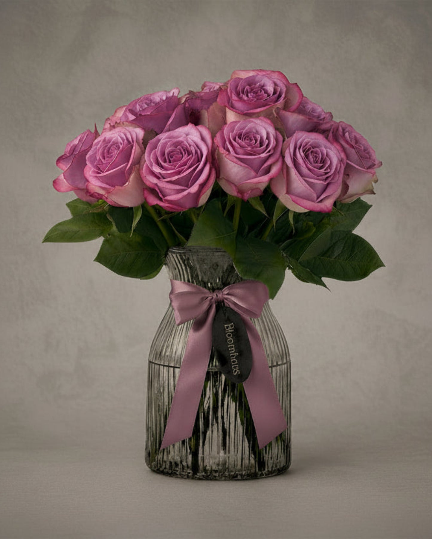 Lilac roses in a glass vase, part of the Rose Edit 10 stem rose arrangement by BLOOMHAUS MELBOURNE, perfect for floral decor.