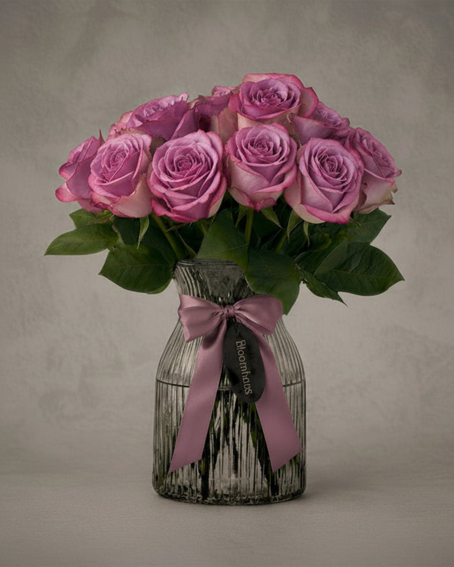 Lilac roses in a glass vase, part of the Rose Edit 10 stem rose arrangement by BLOOMHAUS MELBOURNE, perfect for floral decor.