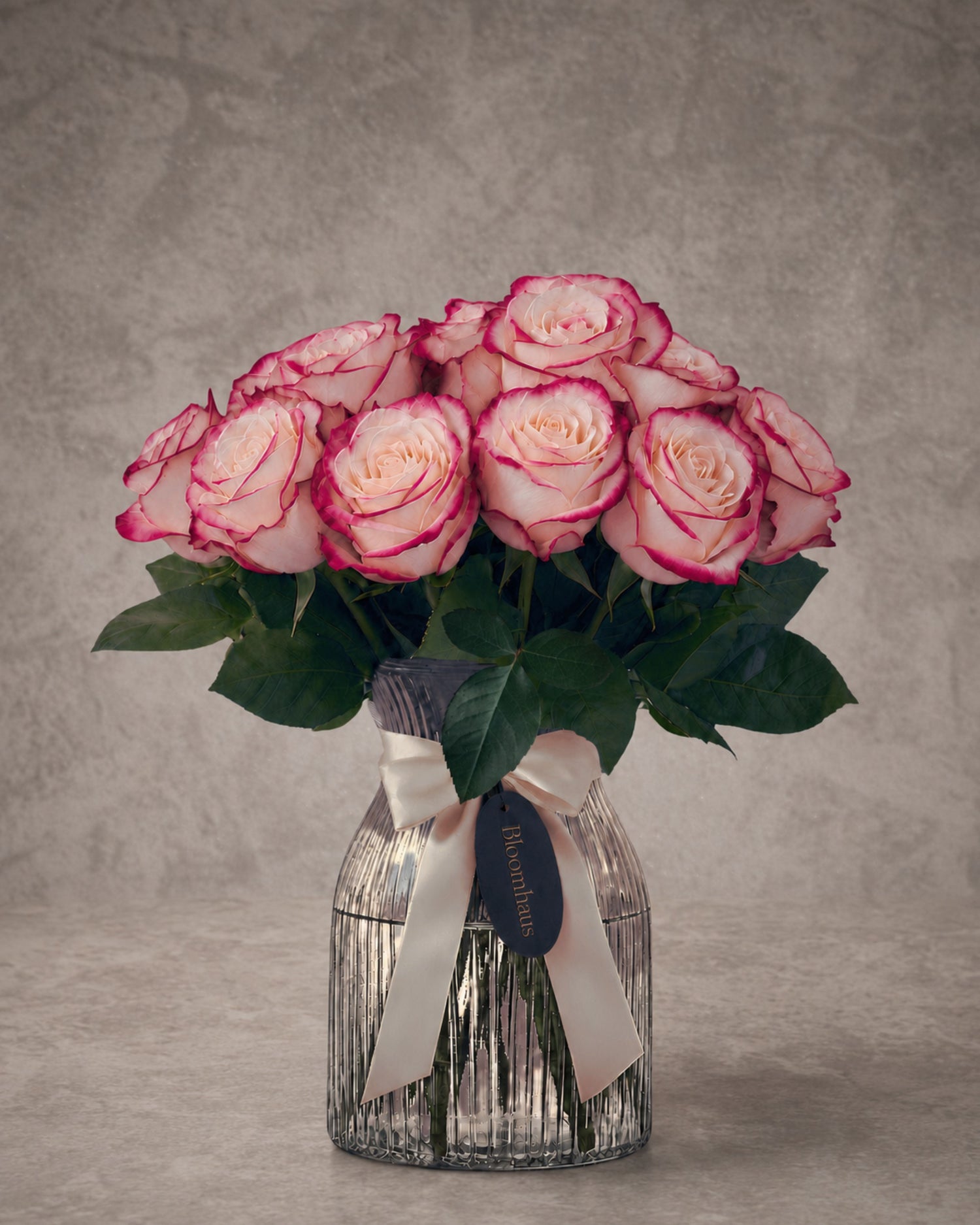Variegated white roses with deep pink edges in a glass vase, part of the Rose Edit 10 Stem Rose Arrangement by BLOOMHAUS MELBOURNE