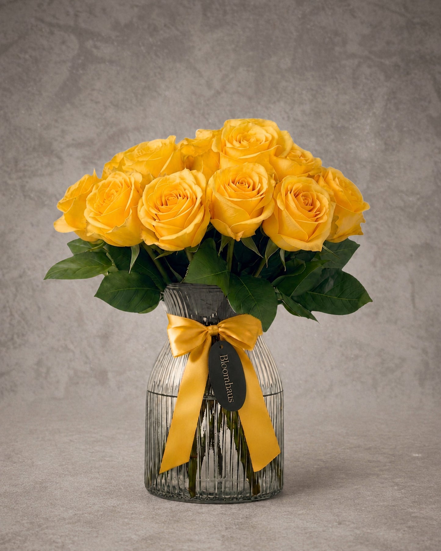 Yellow rose stems arranged in a clear glass vase, part of the Rose Edit collection by BLOOMHAUS MELBOURNE.