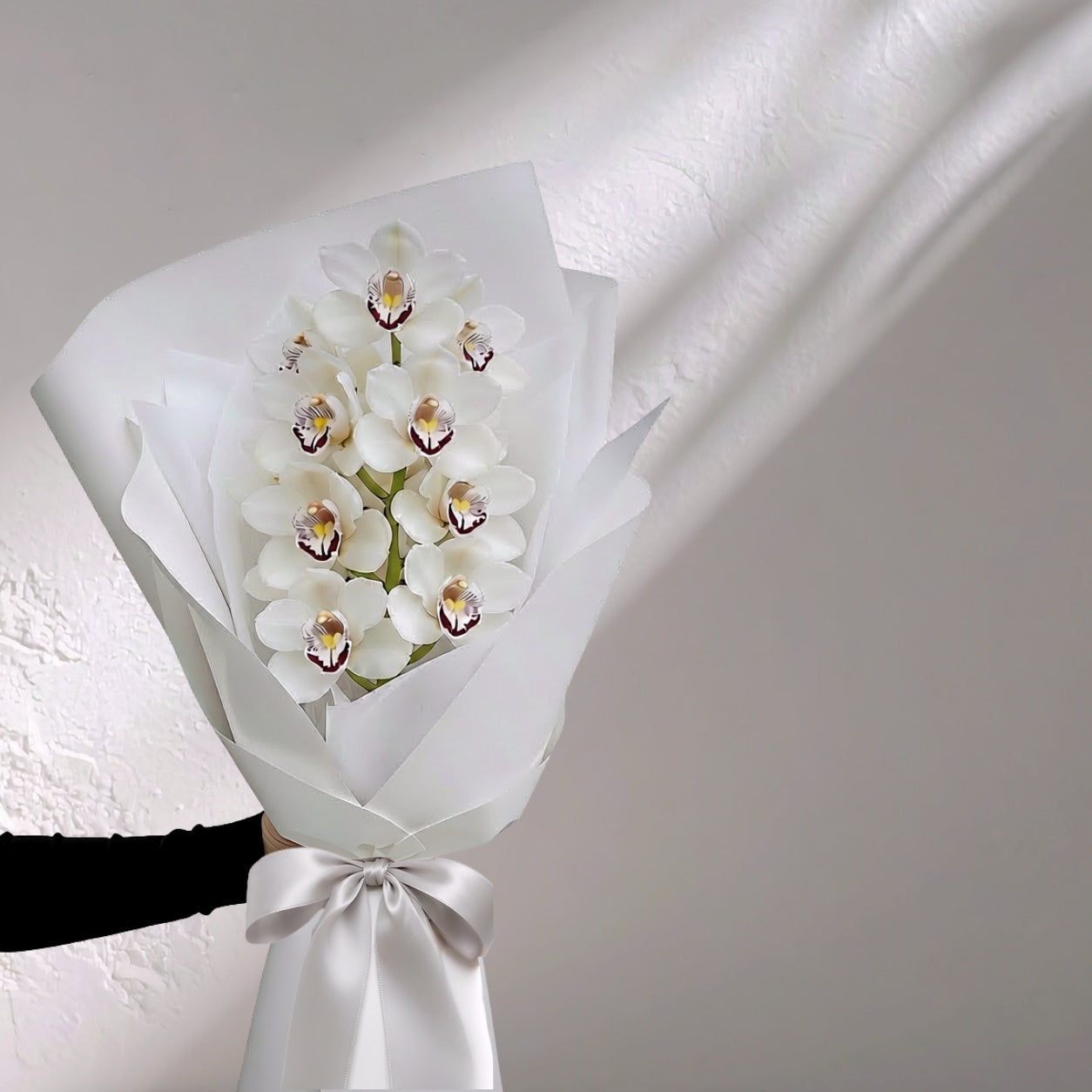 White Cymbidium orchid in bloom, fresh floral arrangement by BLOOMHAUS MELBOURNE featuring elegant orchid flowers.