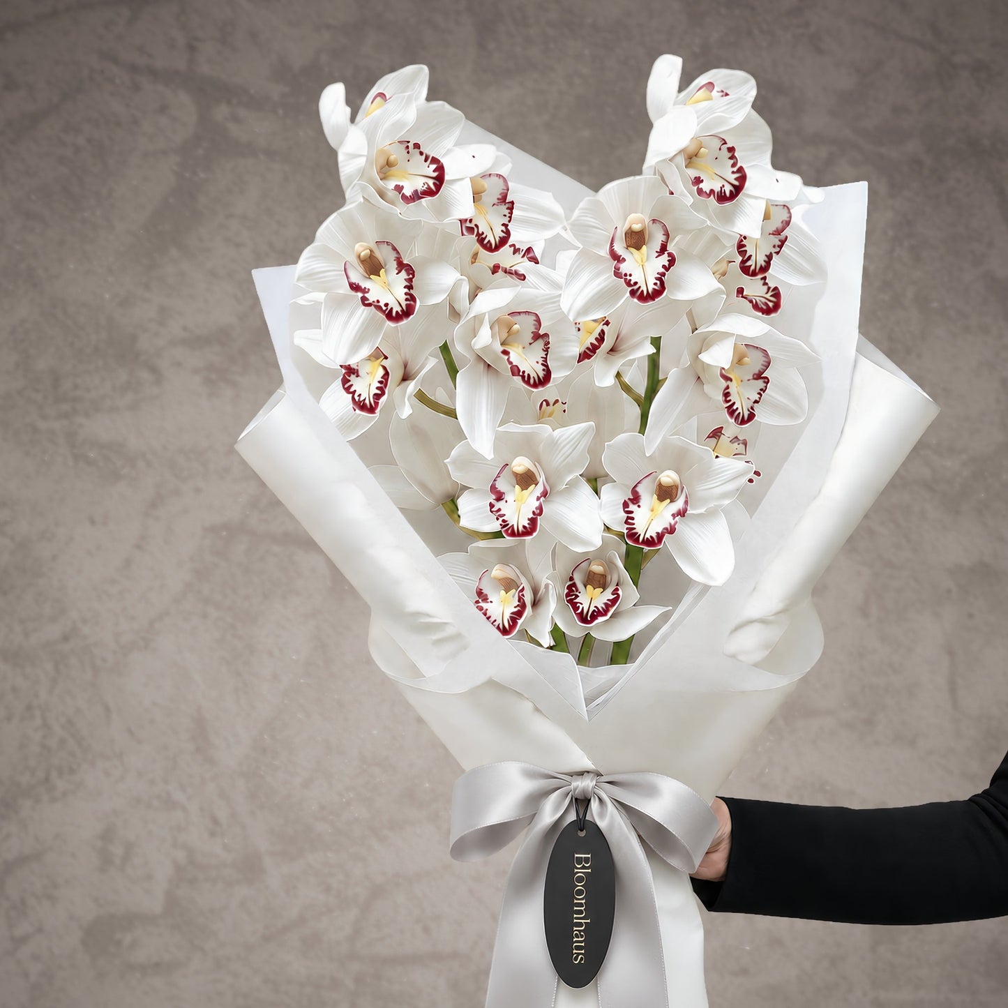 Luxury white cymbidium orchid bouquet in sculptural white wrapping with silver ribbon by Bloomhaus Melbourne