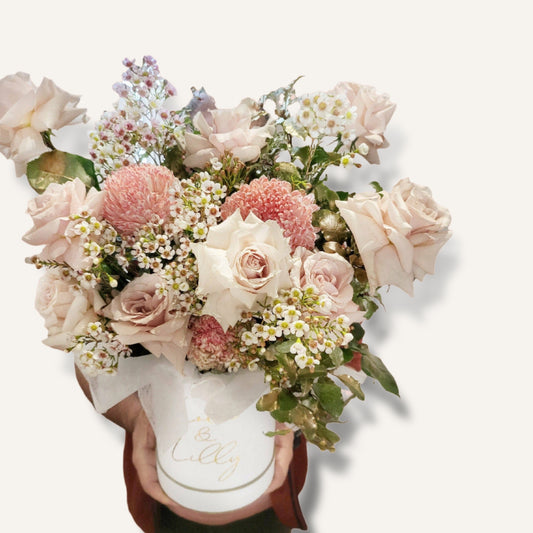 Gola flowers in a personalized hatbox featuring radiant roses, disbuds, and seasonal blooms arranged beautifully.