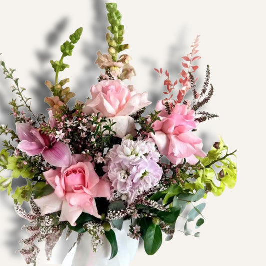 Soft pink roses and lilac seasonal flowers arranged in a ceramic pot, featuring reflexed roses from Bloomhaus Melbourne.
