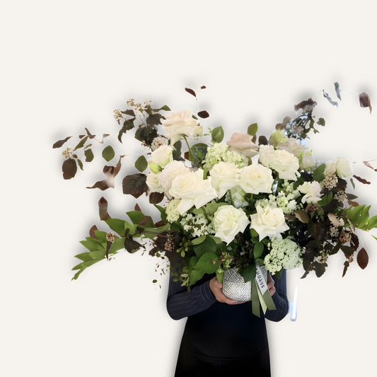 Fresh bespoke flower arrangement in a ceramic pot by BLOOMHAUS MELBOURNE, featuring vibrant blooms and greenery.