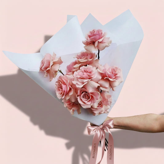 Bloomhaus Melbourne Bouquet of pink roses wrapped in light blue paper against a pink background
