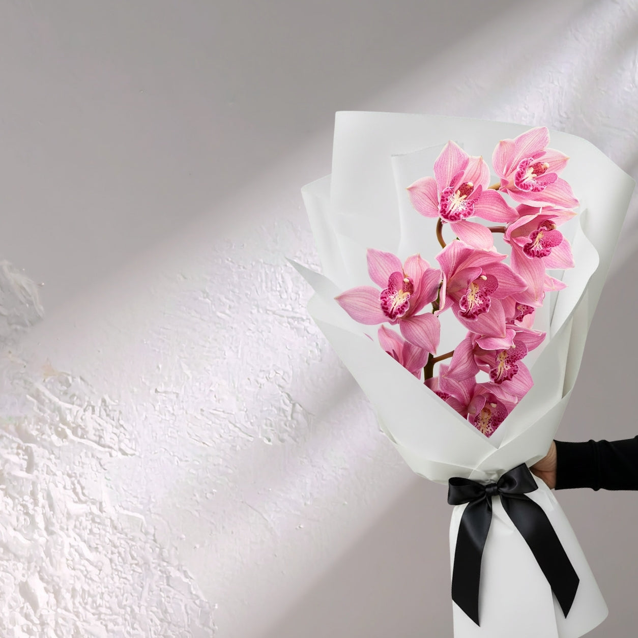 Pink Cymbidium orchid flowers in a lush floral arrangement by BLOOMHAUS MELBOURNE, showcasing elegant orchid blooms.